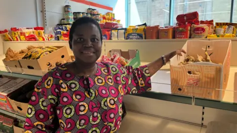 Woman smiling with food shop behind her.