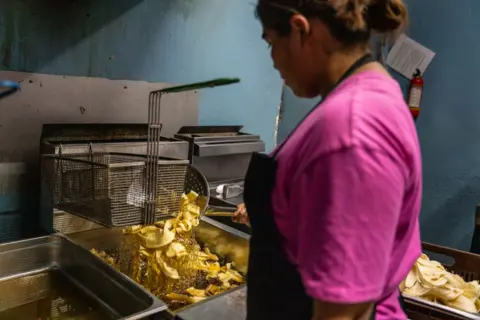 Fritz Pinnow a woman in the Locos Ploss (Crazy Chickens) is fringing banana strips. Comayagua, March 8, 2025