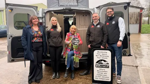 Malvern Hills District Council A group of five people stand in front of an open camper van, with a sign for a camper conversion business placed beside them.