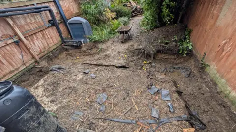 A garden with upturned soil and part-dug foundations. 