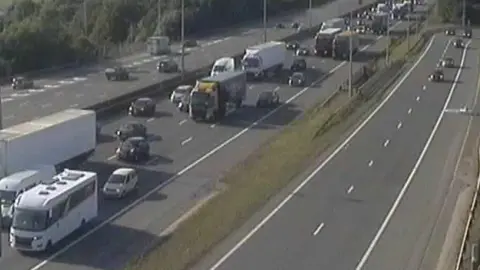National Highways Traffic approaching junction nine on the M1 in Hertfordshire. The cars, lorries and vans are backed up.