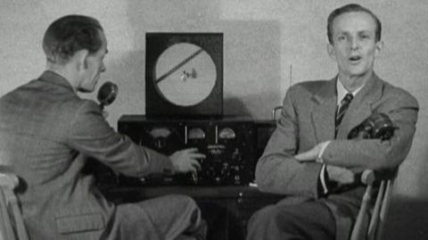 Tv viewer Mr Allen and a BBC reporter sit at a radio transmitter