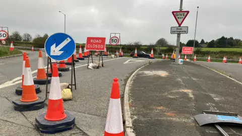 A road closure on the A30 in Cornwall. Orange and white traffic cones have been set out on the road where a closure was in place. a 50 mph speed limit sign is also in place on the road. 