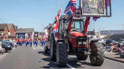 Pacemaker A red tractor is at the front of a parade draped in Union flags.