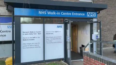 The entrance to Norwich's NHS walk-in centre. There is an automatic door and a large window to the left.