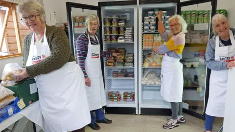 Clare Walsh Volunteers from the West Somerset Food Cupboard are stood in front of a fridge fully stocked with produce