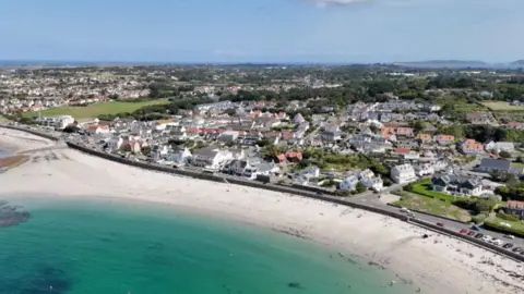 BBC An aerial shot of Guernsey from above with a blue sea and housing in the background