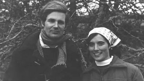 Farms for City Children The picture shows two people standing close together outdoors in what looks like a wooded or rural setting. It appears to be an older black‑and‑white photograph. One person is wearing a heavy coat with a scarf wrapped around their neck. The other is wearing a jacket and a patterned headscarf tied around their hair. 