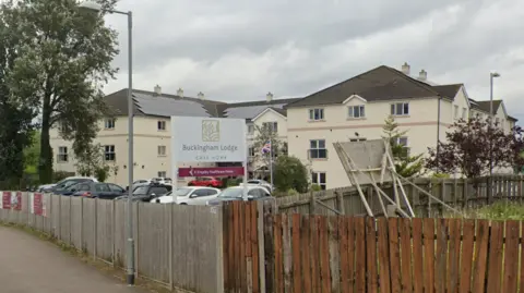 Google Maps A view of Buckingham Lodge Care Home, in Watton, from the road. It is a cream-coloured building sitting behind a car park which is fenced off.