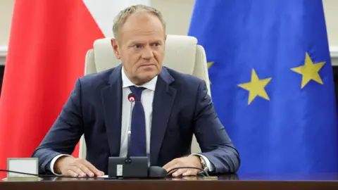 EPA/Shutterstock Prime Minister Donald Tusk speaks during an extraordinary government meeting at the Chancellery of the Prime Minister in Warsaw. Behind him are the flags of Poland and the European Union