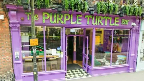 Google The Purple Turtle Bar and Music venue, is a red brick building with a purple frontage.