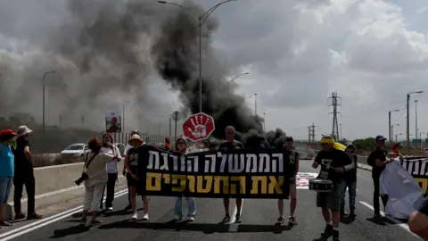 EPA protestētāji blakus riepu dedzināšanai uz galvenā ceļa Petah Tikva, Izraēlā