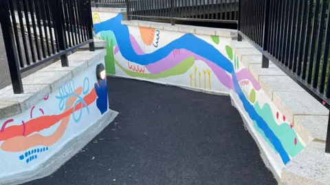 Alastair Wren A freshly painted underpass, with new flooring, white painted walls and black painted railings. 