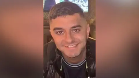 Family handout Jordan Hogg smiles at the camera. He has faint stubble and short black hair.