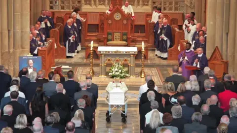 Salford Cathedral People at Salford Cathedral sit on pews as a coffin is at the front