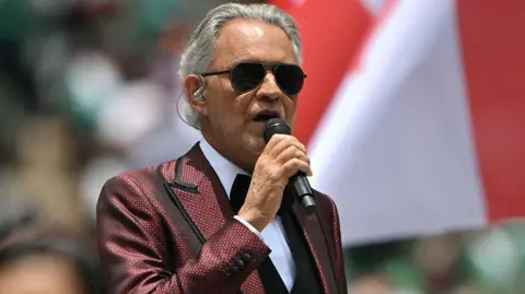 Getty Images Bocelli wearing a red patterned suit with a tuxedo.