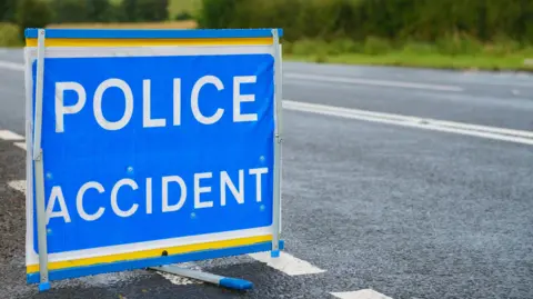 Getty Images Blue police accident sign with white writing on the side of a road 