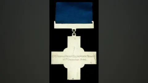 Noonans The back of a George Cross medal on a dark blue ribbon. The inscription reads CPO Reginald Vincent Ellingworth, 20th December 1940