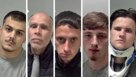 Five police mugshots are lined up next to one another. Four of the men appear to be in their late teens to early 20s whilst one defendant, Hunt, is older in appearance. He has a bald head and a grey beard. Taylor-Bates appears with brown swept back hair and a neck brace. 