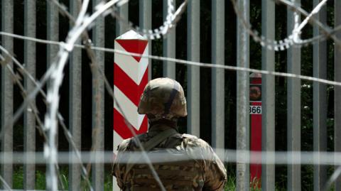 A soldier stands guard near the fence on the Belarusian-Polish border