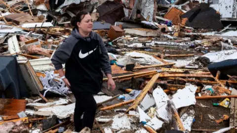 A woman stands amidst rubble in Poplar Bluff, Missouri on March 15, 2025