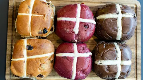 A variety of hot cross bun flavours on a wooden board.