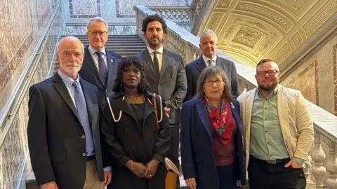 Courtesy of Gemma Hickey Seven people of different races and genders stand on marble stairs in the Vatican wearing formal attire.