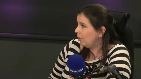 Falkirk councillor Laura Murtagh sitting in the Scotcast studio, she has shoulder length dark hair and a black and white striped top.