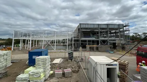 The shell of a leisure facility in Leighton Buzzard is under construction under grey cloud