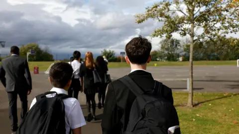 Getty Images Boys wearing black blazers white shirts walk through a playground