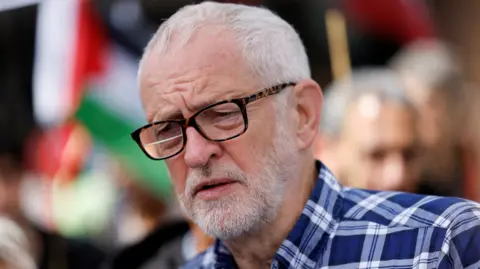 Reuters Independent MP Jeremy Corbyn wearing a blue plaid shirt and tortoiseshell glasses