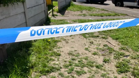 Blue and white police tape covers a patch of land