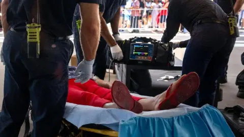 A person lies on a stretcher to be treated for heat exhaustion