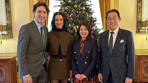 X/@kishida230 Justin Trudeau, Katy Perry, Fumio Kishida, and his wife, Yuko in a room with a Christmas tree