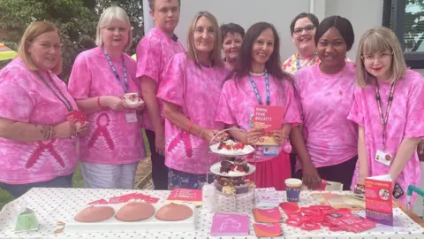 NWAFT Attendees pose in pink T-shirts in front of an afternoon tea display