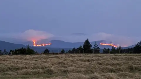Stretch of mountains in the Cairngorms with wildfires burning across a large area