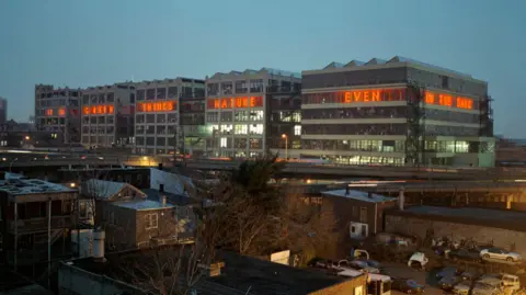 Kenny Trice/MEC, studios indestructible language installed in 2006 at the American Can Company buildings on the Pulaski Skyway in  Jersey City, New Jersey for the temporary installation with the Precipice Alliance founded by Joel Sternfeld and Donna Wingate.