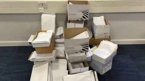 BBC/Fay Wilson Boxes filled with paper, there are around twenty boxes, which could contain many thousands of pieces of paper, which presumably all have patient information on them