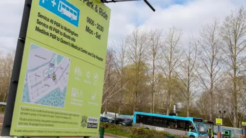 A totem sign at a park and ride site, with a bus in the background