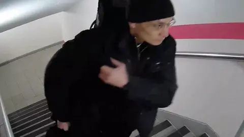 A Polícia de Northumbria ainda imagem de imagens de CCTV de um homem todo vestido de preto, com um chapéu preto e carregando uma bolsa subindo as escadas.