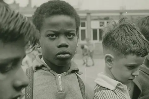 Estate of John Blakemore provided by Coventry University A close up of four boys, one of which is looking at the camera, wearing a quarter zip 