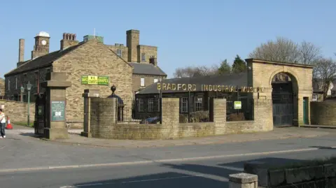 John Yeadon Light coloured brick mill buildings with a sign that reads: Bradford Industrial Museum