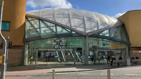 Barnsley Interchange, pictured from the outside. The building comprises a glass dome with yellow blocks on either side.