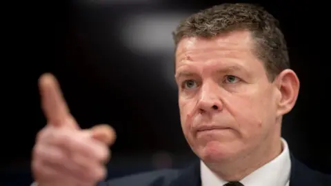 Getty Images Rhun ap Iorwerth, wearing a dark suit and white shirt, points his finger forward