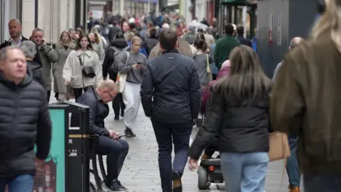 The latest Opinions and Lifestyle survey asked Jersey adults about their wellbeing. Image shows people walking on a busy high-street on a grey day in St Helier.