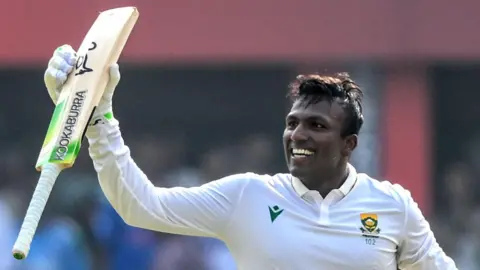 Senuran Muthusamy raises his bat after scoring a century for South Africa