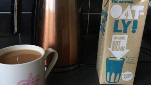 Oatly carton with a cup of tea next to it