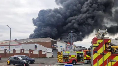 Melvin Cooper, the factory fire sent large columns of smoke in the air. Two extinguishing devices can be seen outside.
