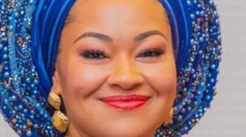 A close-up photo of Nigerian senator Natasha Akpoti- Uduaghan wearing a blue headscarf and gold earrings.