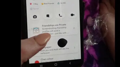 A woman's hand holding a smartphone with the Snapchat app on screen.